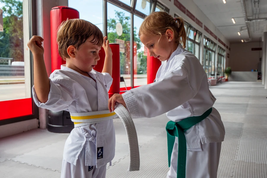 Ein Kind bindet einem anderen Kind den Taekwondo-Gürtel