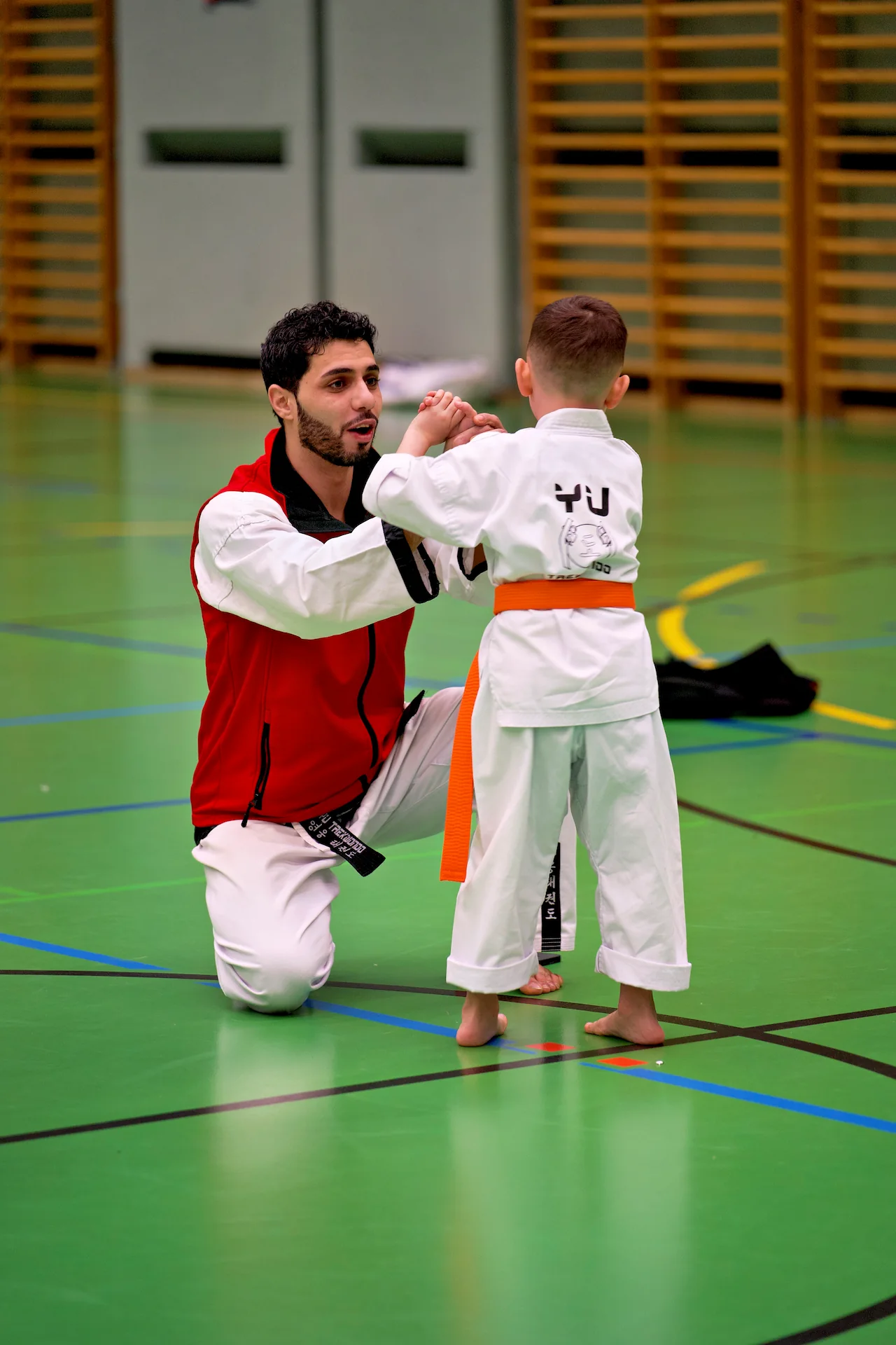 Kampfsport-Trainer vermittelt Kindern im Training Werte wie Respekt beim gemeinsamen Üben in der Sporthalle.