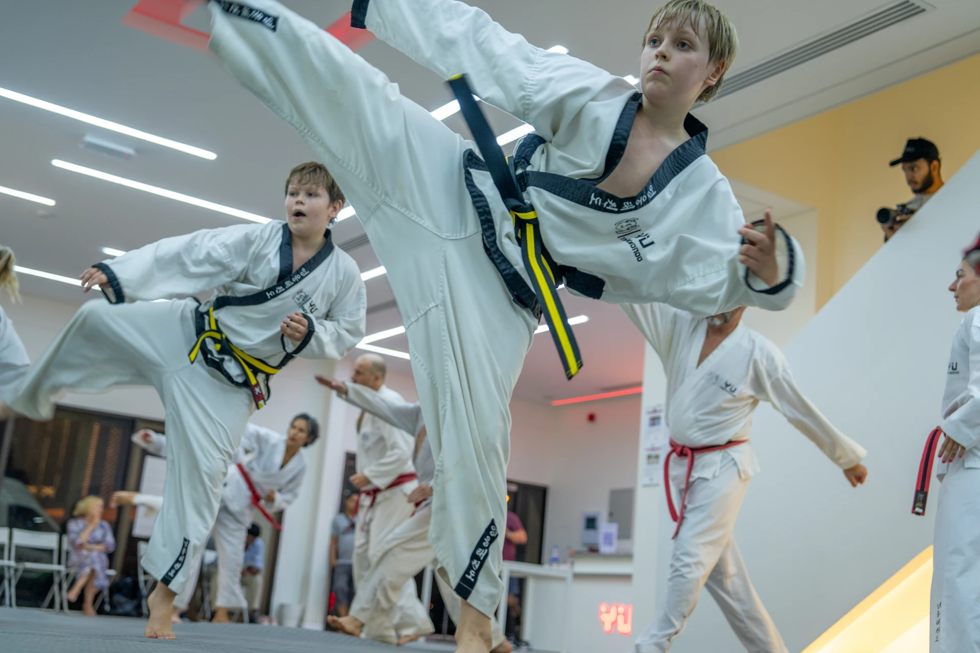 Jugendliche beim Taekwondo Training führen synchron hohe Kicks in einer modernen Kampfsportschule aus.